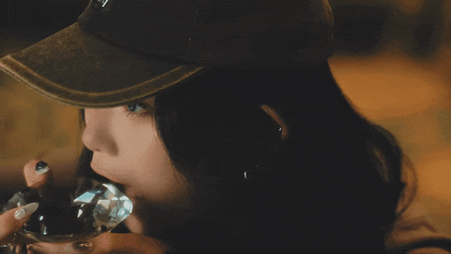 a woman wearing a hat with the letter y on it drinks from a glass