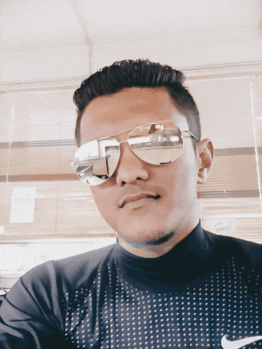 a man wearing sunglasses and a nike shirt poses for a photo