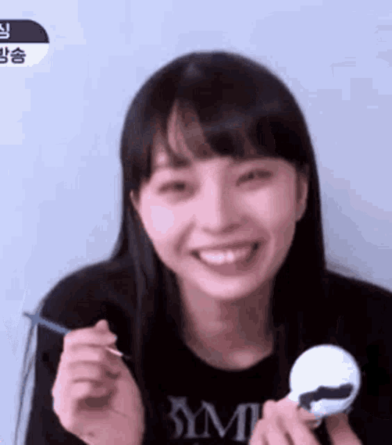a young woman is smiling while holding a toy and a spoon in her hand .