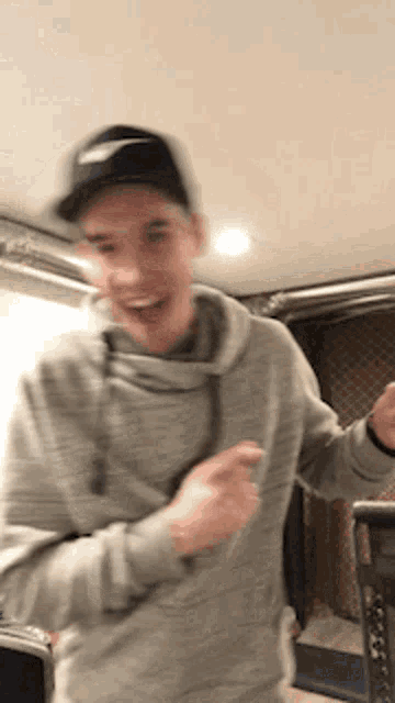 a man wearing a nike hat and a grey sweatshirt is dancing