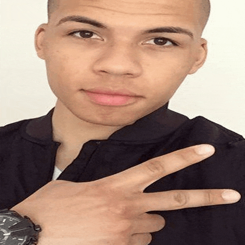 a young man is wearing a watch and making a peace sign with his fingers .