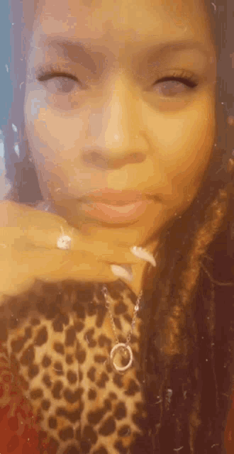 a woman is wearing a leopard print shirt and a necklace with a circle pendant .