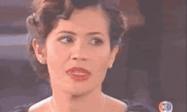 a close up of a woman 's face with a necklace and red lipstick .