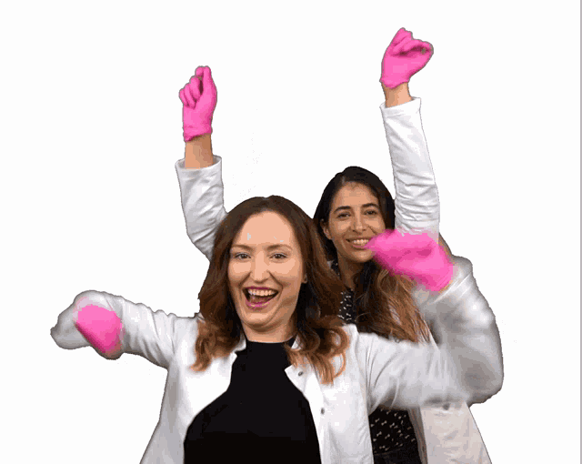 two women wearing white coats and pink gloves are celebrating