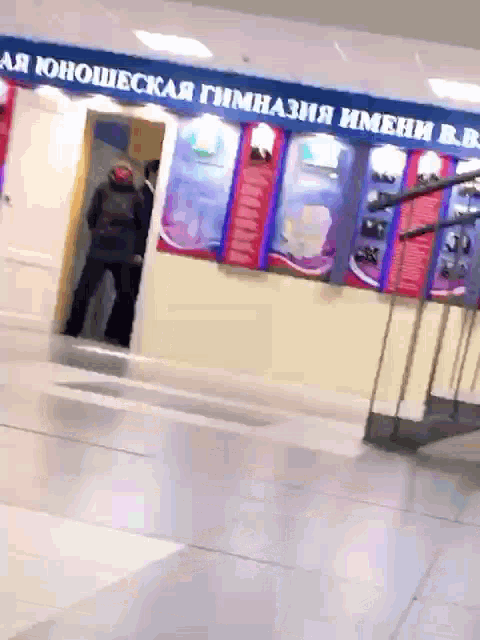 a man standing in front of a sign that says " aa юношеская гимназия имени b.b. "