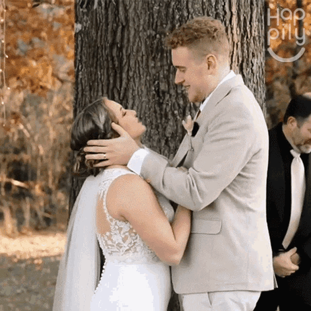 a bride and groom kissing in front of a tree with the word hop on the bottom right