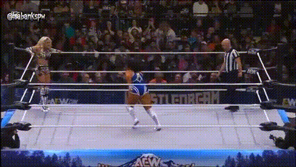 two women are wrestling in a wrestling ring with a referee in the background .