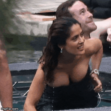a woman in a black dress is sitting in a pool with a man .