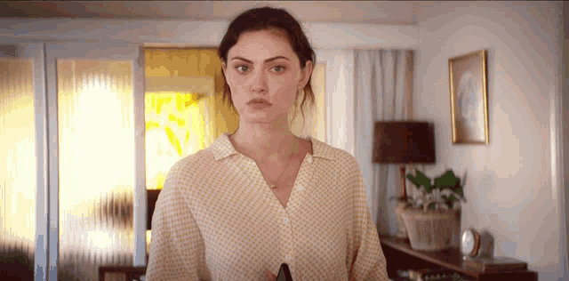 a woman stands in a living room with a clock on the table