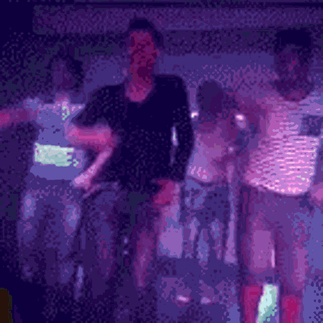 a group of people are dancing together in a dark room .