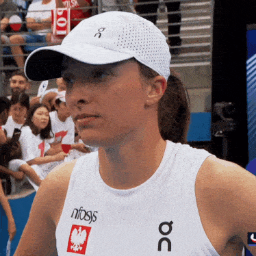 a woman wearing a white hat and a white tank top that says nifsys