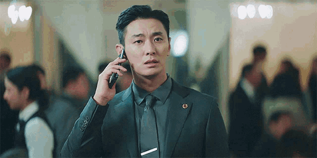 a man in a suit and tie is talking on his cell phone