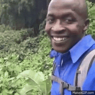 a man wearing a blue shirt and a backpack is smiling in a field .