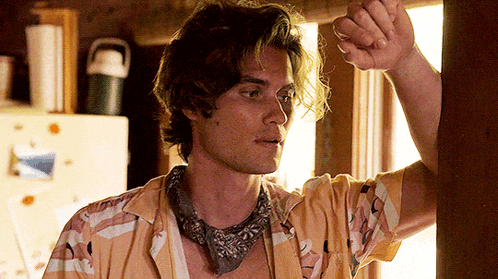 a young man wearing a bandana and a yellow shirt is standing in front of a window .