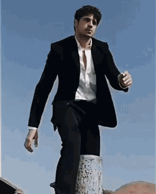 a man in a suit and white shirt is standing on a post