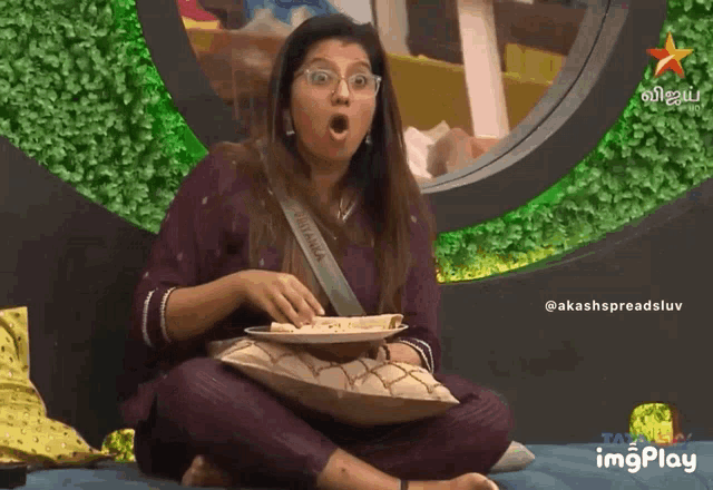 a woman is sitting on a bed holding a plate of food and a star is visible in the background