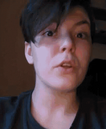 a close up of a person 's face with short hair and a black shirt on .