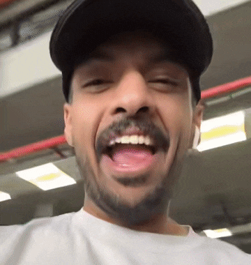 a man with a beard wearing a hat is smiling with his mouth open