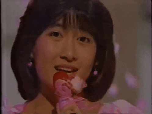 a woman in a pink dress is holding a pink rose in her hand