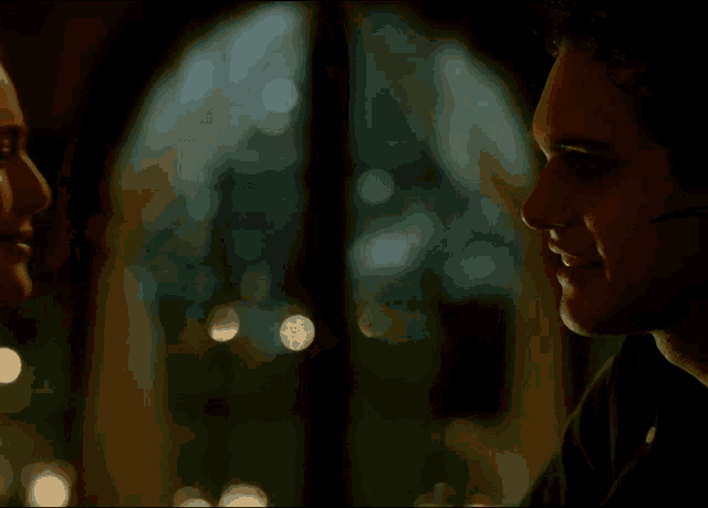 a man and a woman are looking at each other in front of a window