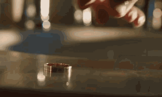 a close up of a person 's hands putting a wedding ring on a table .
