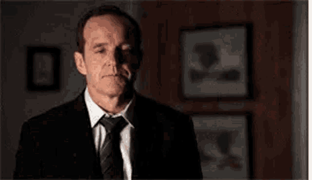 a man in a suit and tie is looking at the camera .