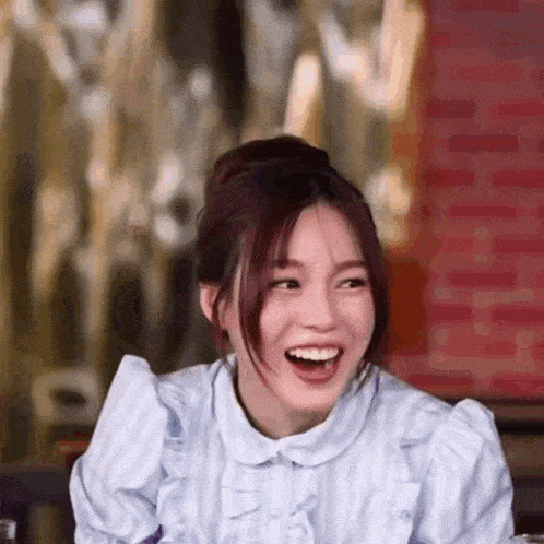 a close up of a woman laughing with her mouth open while sitting at a table .