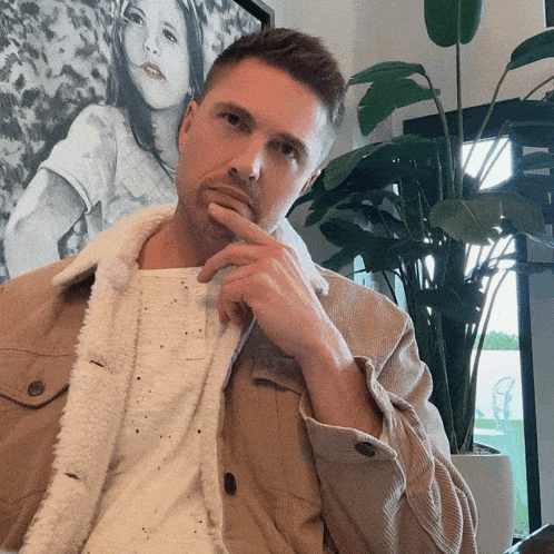 a man with his hand on his chin in front of a painting of a girl