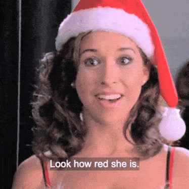 a woman is wearing a santa hat and says look how red she is