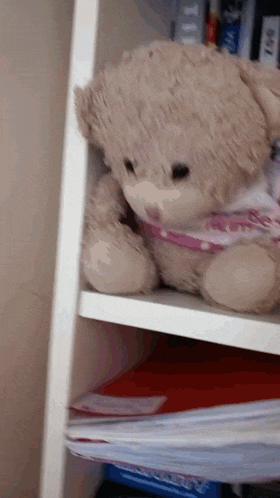 a teddy bear is sitting on a shelf next to a box that says ' a ' on it