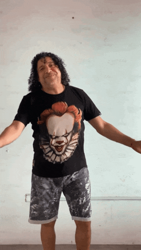 a man with curly hair is wearing a black pennywise t-shirt