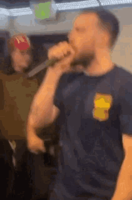a man with a beard is singing into a microphone while another man watches .