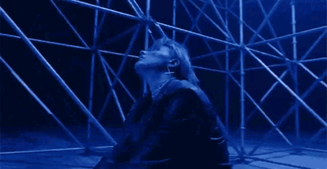 a man in a leather jacket is sitting in front of a scaffolding .