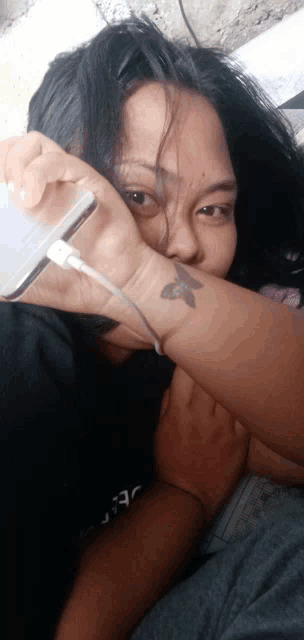 a woman with a tattoo on her wrist holds a phone
