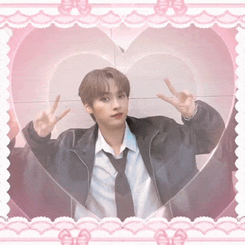 a young man in a black jacket and tie giving the peace sign