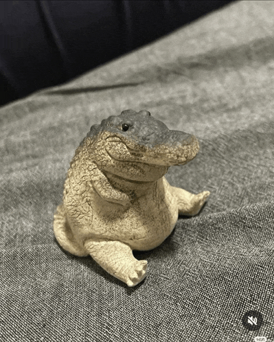 a statue of a crocodile is sitting on a grey couch