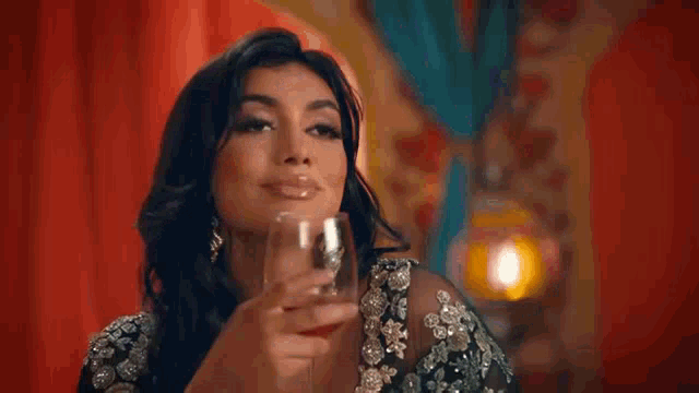 a woman in a black dress is holding a glass of wine .