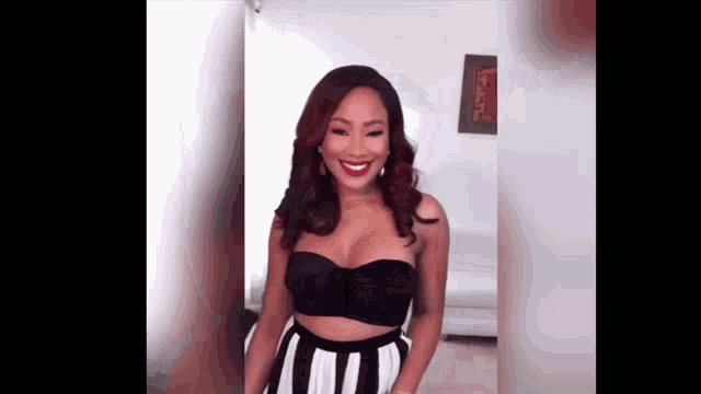 a woman in a black crop top and striped skirt is smiling for the camera .