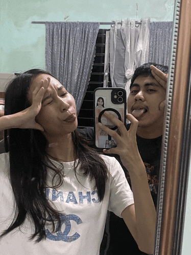 a man and a woman are taking a selfie in a mirror