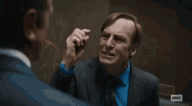 a man in a suit and tie is talking to another man with the letters a and m on the bottom