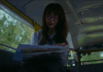 a woman wearing glasses is reading a magazine with a pink butterfly on the cover