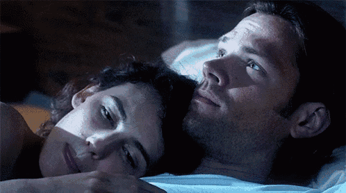 a man and a woman are laying next to each other on a bed .