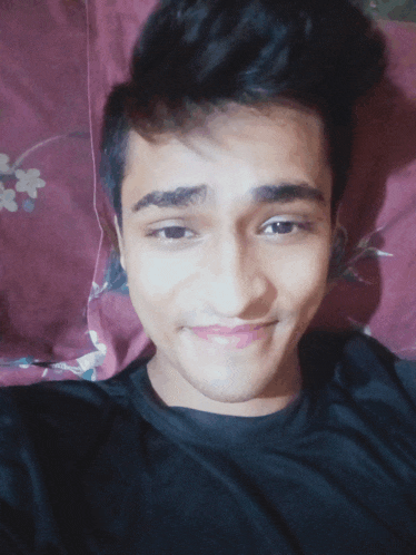 a young man laying on a bed with a purple pillow