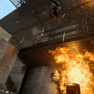 a man is hanging from a rope while a barrel is on fire