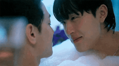 a couple of men are kissing in a bathtub .
