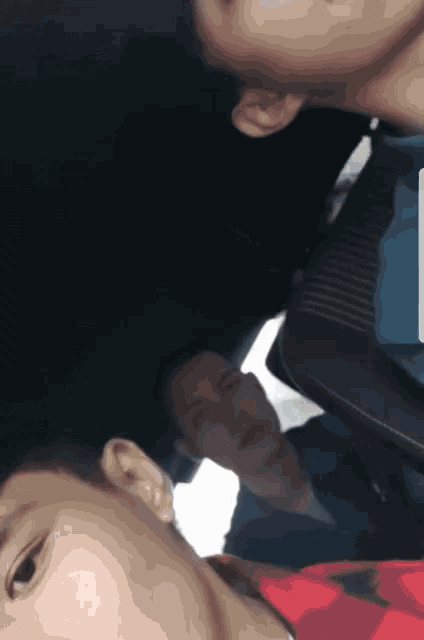 two men are sitting in a car and one is wearing a blue shirt