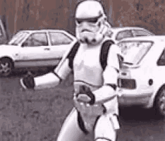 a storm trooper is walking down the street in front of a parking lot .