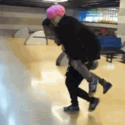 a person wearing a pink helmet is carrying another person on their shoulders