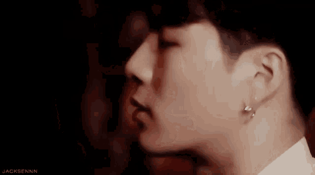 a close up of a man 's face with his eyes closed and earrings on .