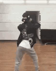 a person is dancing in a room with a wooden floor and a white wall .